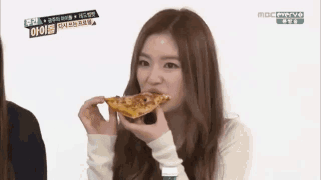 a woman is eating a slice of pizza with a bottle of water next to her .