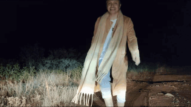 a woman wearing a scarf and a hat is walking in the dark