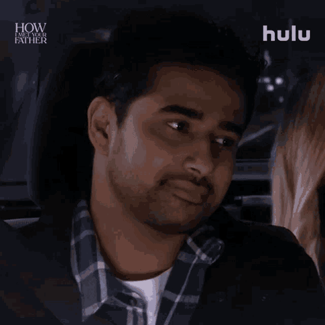 a man in a plaid shirt is sitting in the back seat of a car with hulu written on the bottom