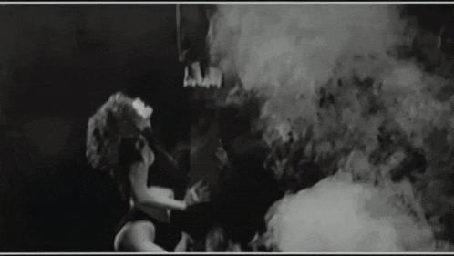 a black and white photo of a woman in a smokey room