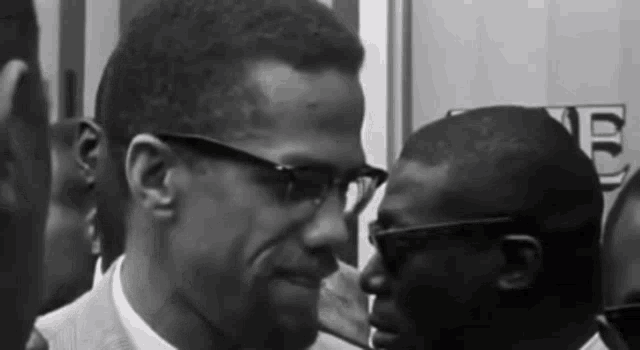 a black and white photo of two men wearing glasses .