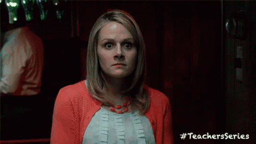 a woman in a red cardigan is making a surprised face while wearing a necklace .