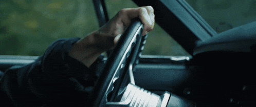 a person is holding a steering wheel in a car