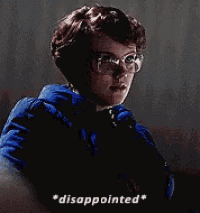 a man wearing glasses and a blue jacket is disappointed .