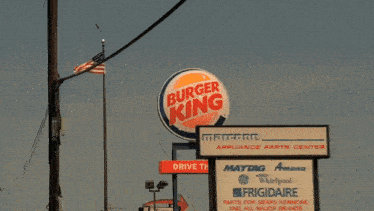 a man in a car looking out the window with a gas station in the background that says gas station