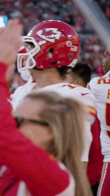 a football player wearing a red helmet with the letter k on it stands in front of a crowd .