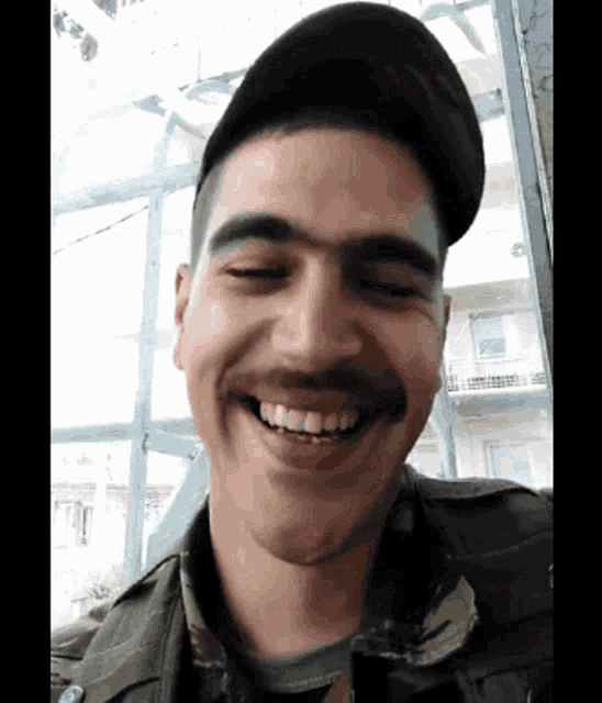 a man with a mustache and a hat is smiling with his eyes closed