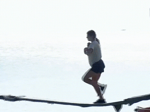 a woman is walking across a board in the ocean