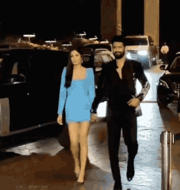 a man and a woman are holding hands while walking down a street