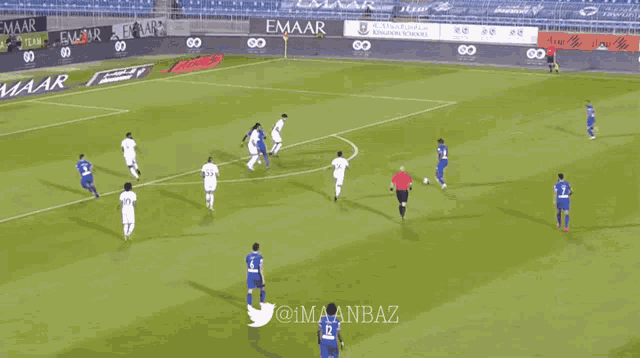 a soccer game is being played on a field with emaar advertisements