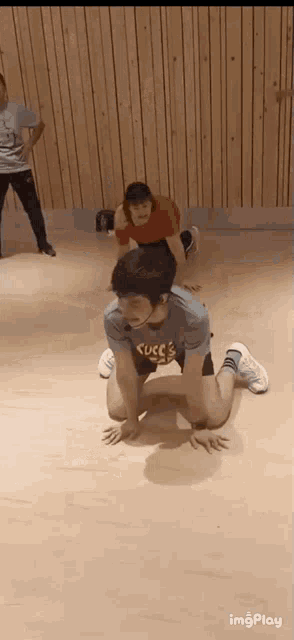 a man is kneeling on the floor in a dance studio while a woman stands behind him .