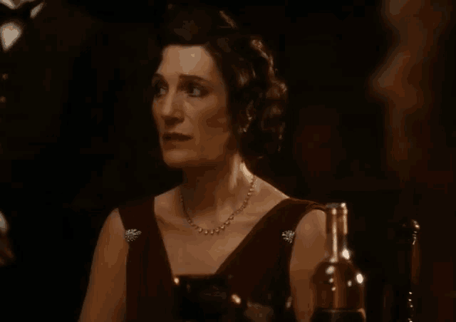 a woman wearing a necklace and a red dress is sitting at a table