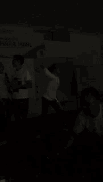 a group of people are standing in a dark room with a sign that says uhara ndhl