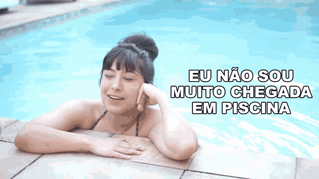 a woman in a bikini is laying in a swimming pool with eu não sou muito chegada em piscina written above her