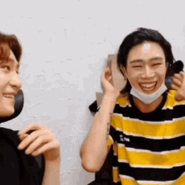 a man wearing a mask is laughing with another man while sitting next to each other .