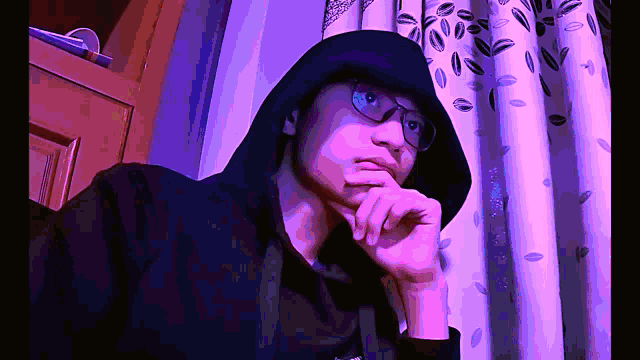 a man wearing glasses and a black hoodie with the word supreme on it