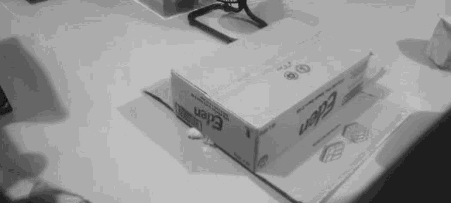 a person is cutting a piece of paper with a knife in front of a cardboard box .
