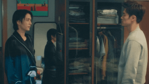 two men are standing in front of a closet with clothes on it