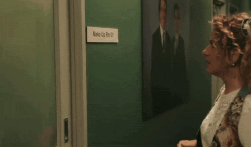 a man and woman are standing in a hallway with a sign that says wake up 8m 01