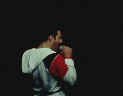 a man singing into a microphone with another man in the background