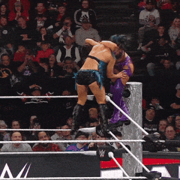two women are wrestling in a wrestling ring with a crowd watching
