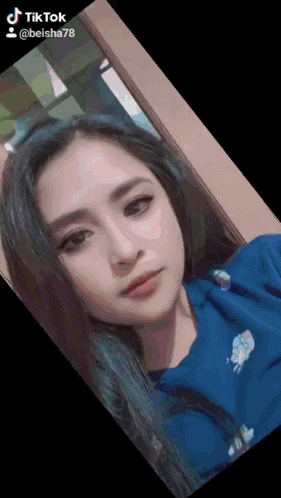 a woman in a blue shirt is looking at the camera