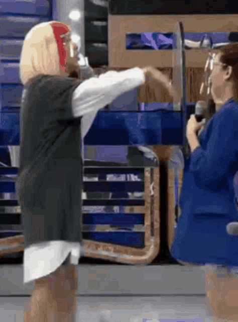 two women are standing next to each other on a stage and one of them is wearing a mask .