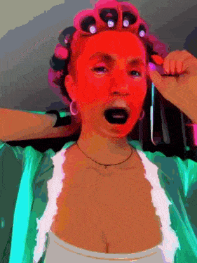 a woman with red curlers on her head is making a funny face