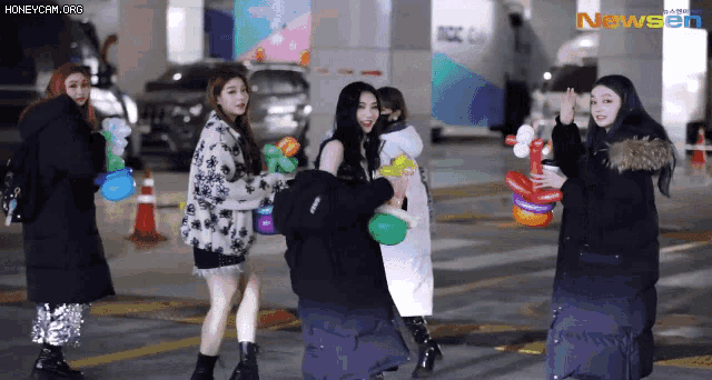 a group of girls are holding balloons in front of a building that says newsen on it