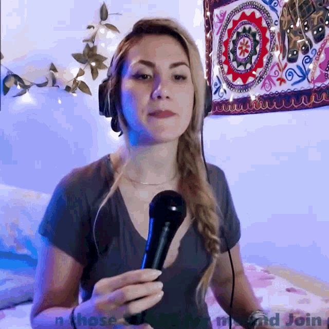 a woman is holding a microphone in front of a tapestry that says " n those and join "