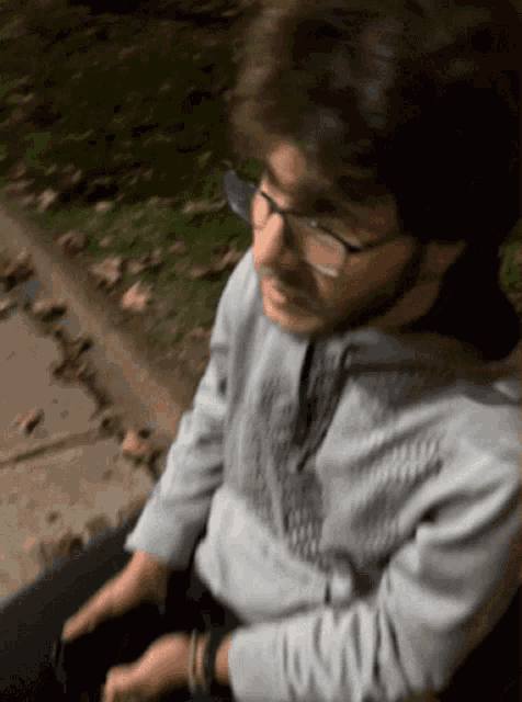 a blurry picture of a man wearing glasses and a grey sweatshirt