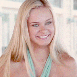 a woman with blonde hair and green eyes smiles for the camera