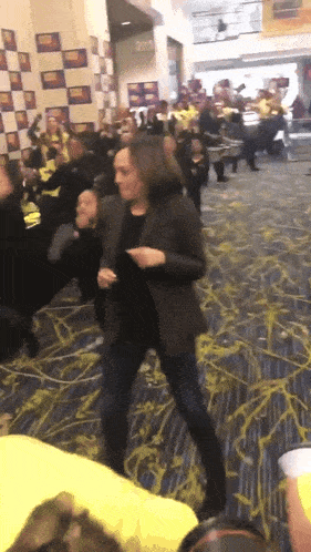 a woman in a black jacket is dancing in front of a crowd of people