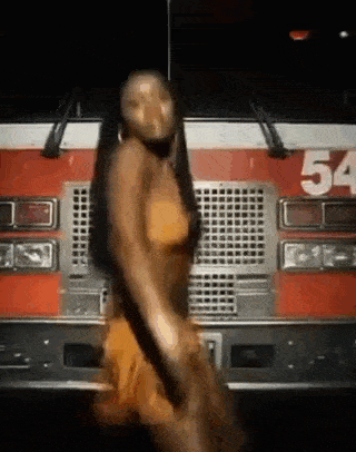 a woman is dancing in front of a fire truck with the number 54 on the front .