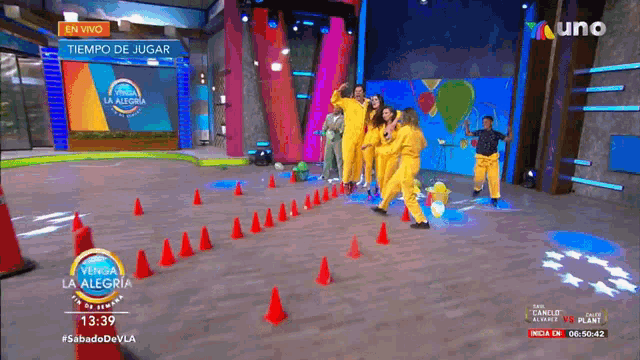 a group of people in yellow jumpsuits are dancing on a stage in front of a sign that says tiempo de jugar