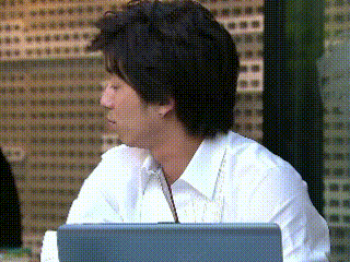 a man in a white shirt sits at a desk with a laptop