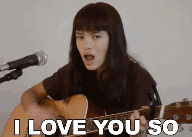 a woman singing into a microphone while holding a guitar that says i love you so on it