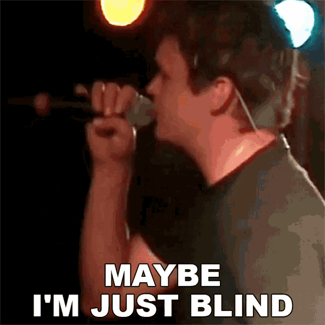 a man is singing into a microphone and says maybe i 'm just blind