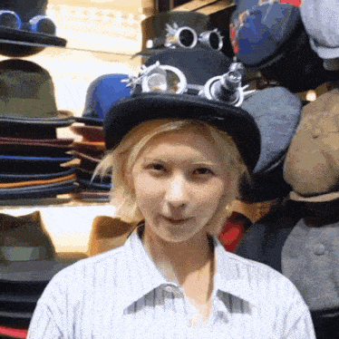 a woman wearing a hat and goggles stands in front of a shelf of hats
