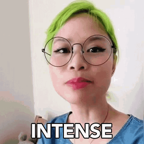 a woman with green hair is wearing glasses and making a face with the word intense written on her face .