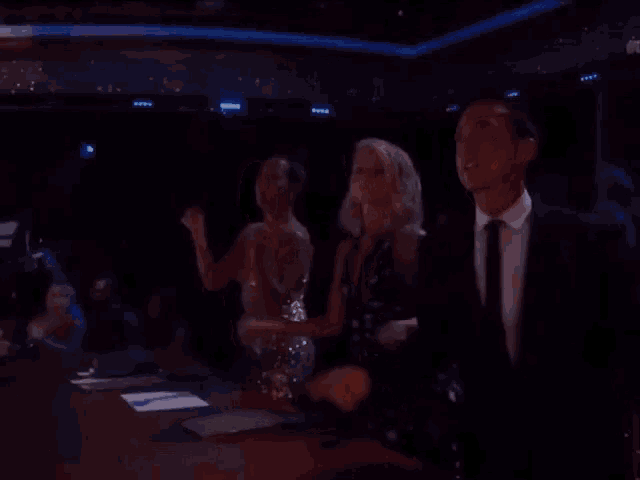 a group of people are dancing in a dark room .
