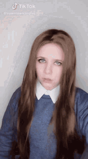 a woman with long brown hair is wearing a blue shirt and white collar