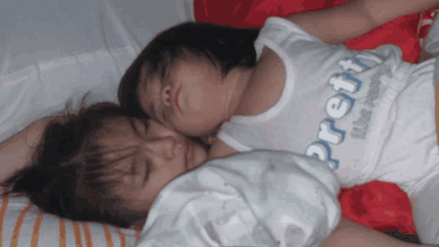 two little girls laying next to each other with one wearing a pretty shirt