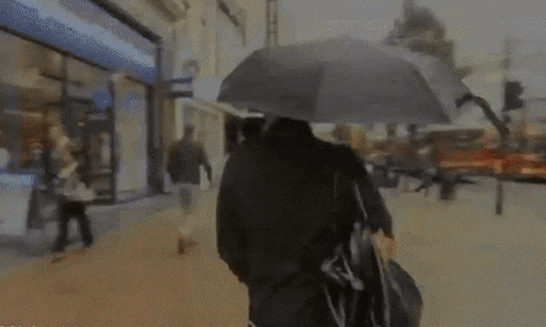 a blurry picture of a person walking down a street with an umbrella in front of a building that says ' hotel '