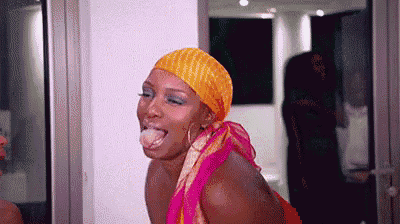 a woman wearing a yellow headband and a pink dress is sticking out her tongue .