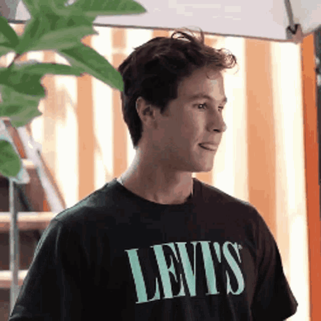 a man wearing a black levi 's t-shirt looks to the side