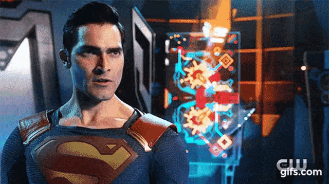 a man in a superman costume is standing in front of a futuristic display .