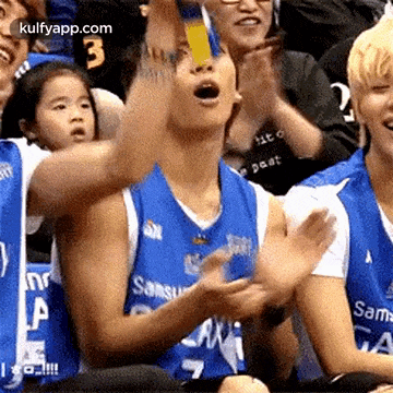 a group of people are sitting in a stadium and one of them is wearing a blue samsung jersey .