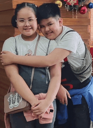 a boy and a girl are posing for a picture and the girl is wearing a purse that says converse on it