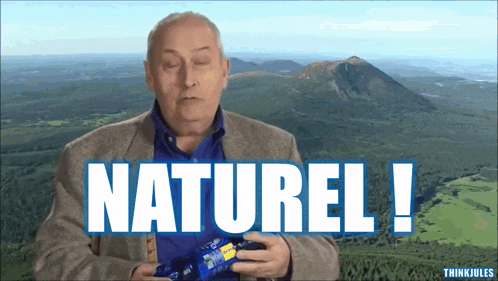 a man in a suit holds a bag of chips and says naturel